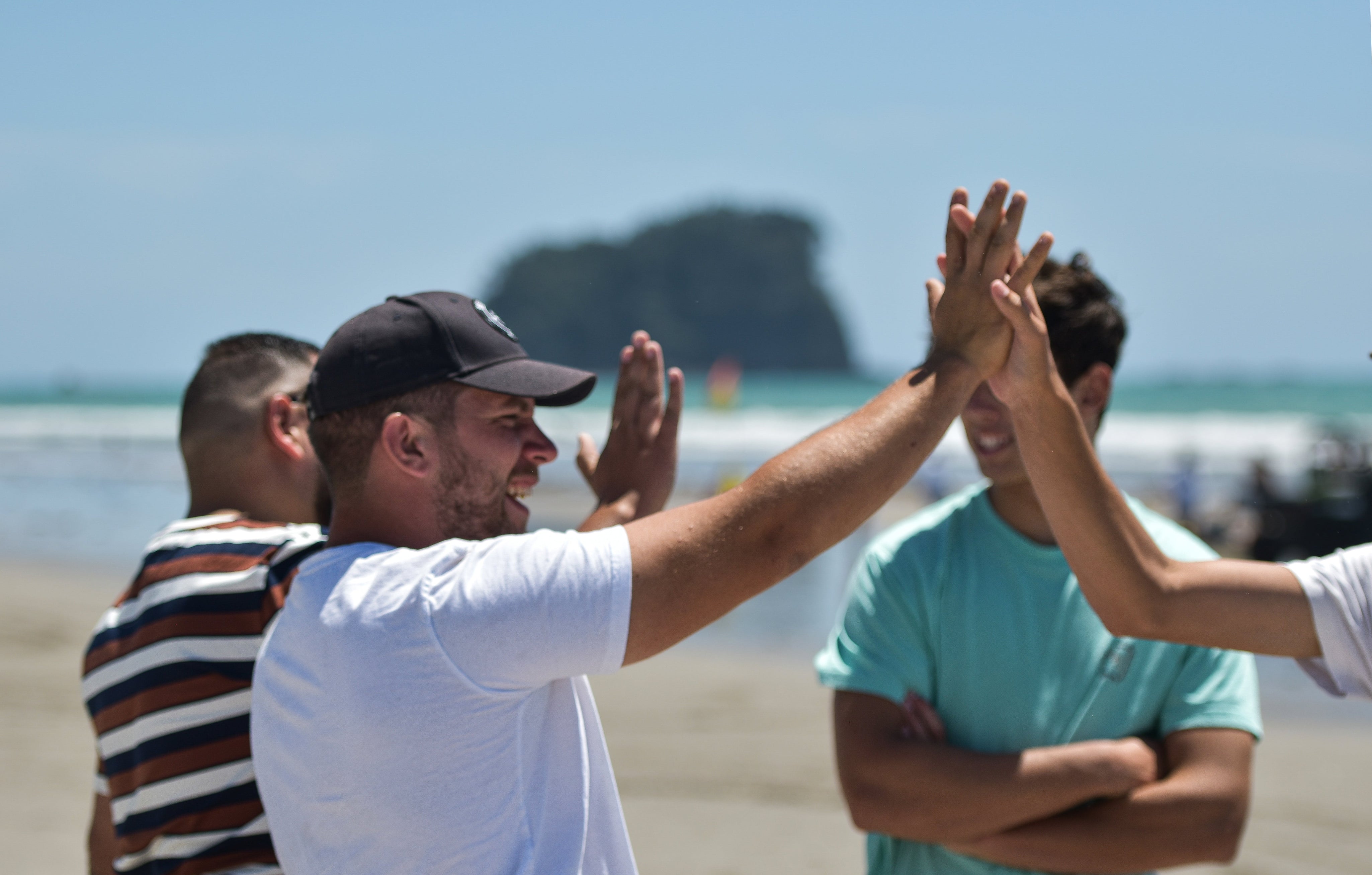 Group of guys high fiving each other on the beach