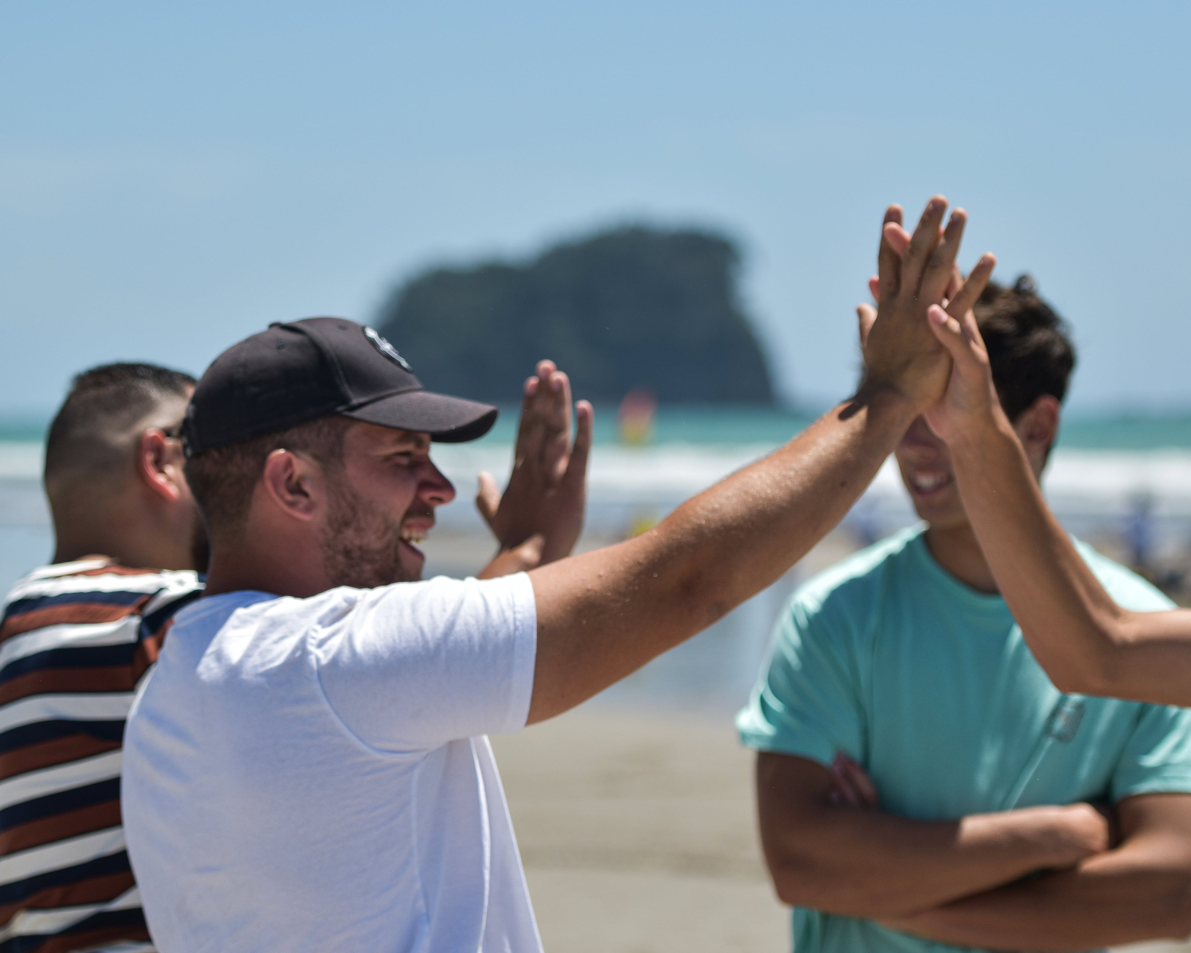 Group of guys high fiving each other on the beach