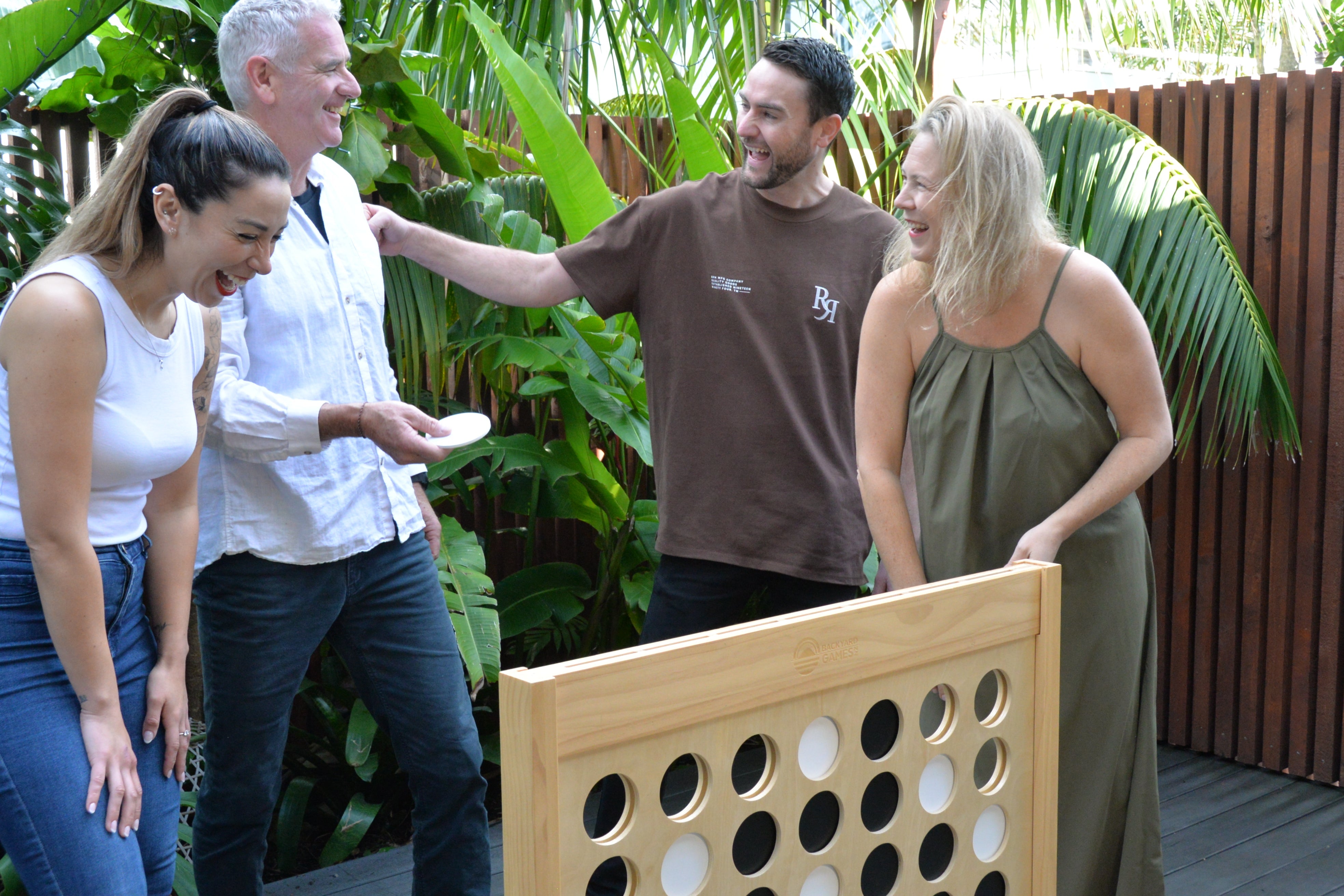 Four adults playing Backyard Games NZ Giant Connect Four 