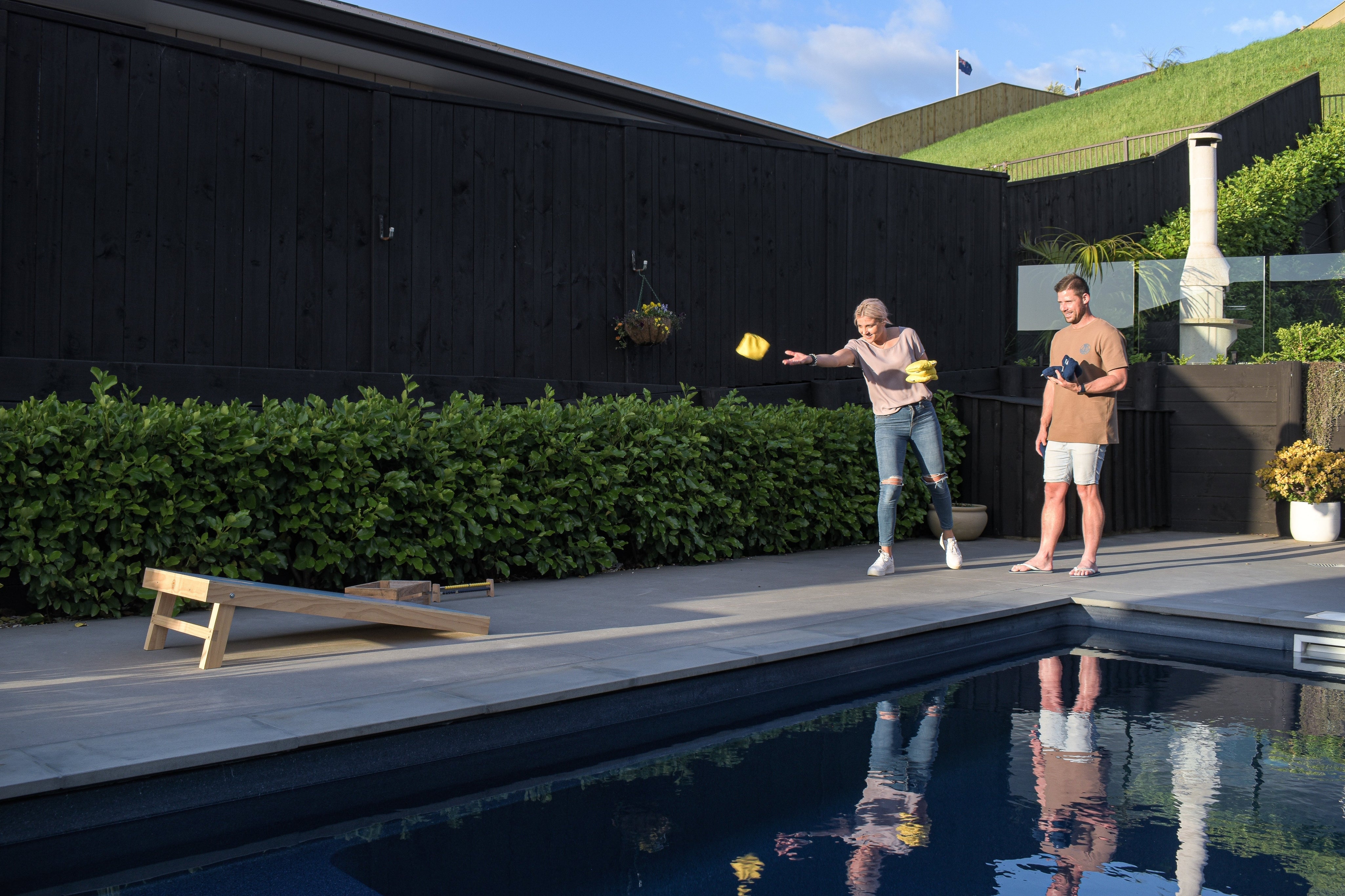 Couple playing Cornhole by pool