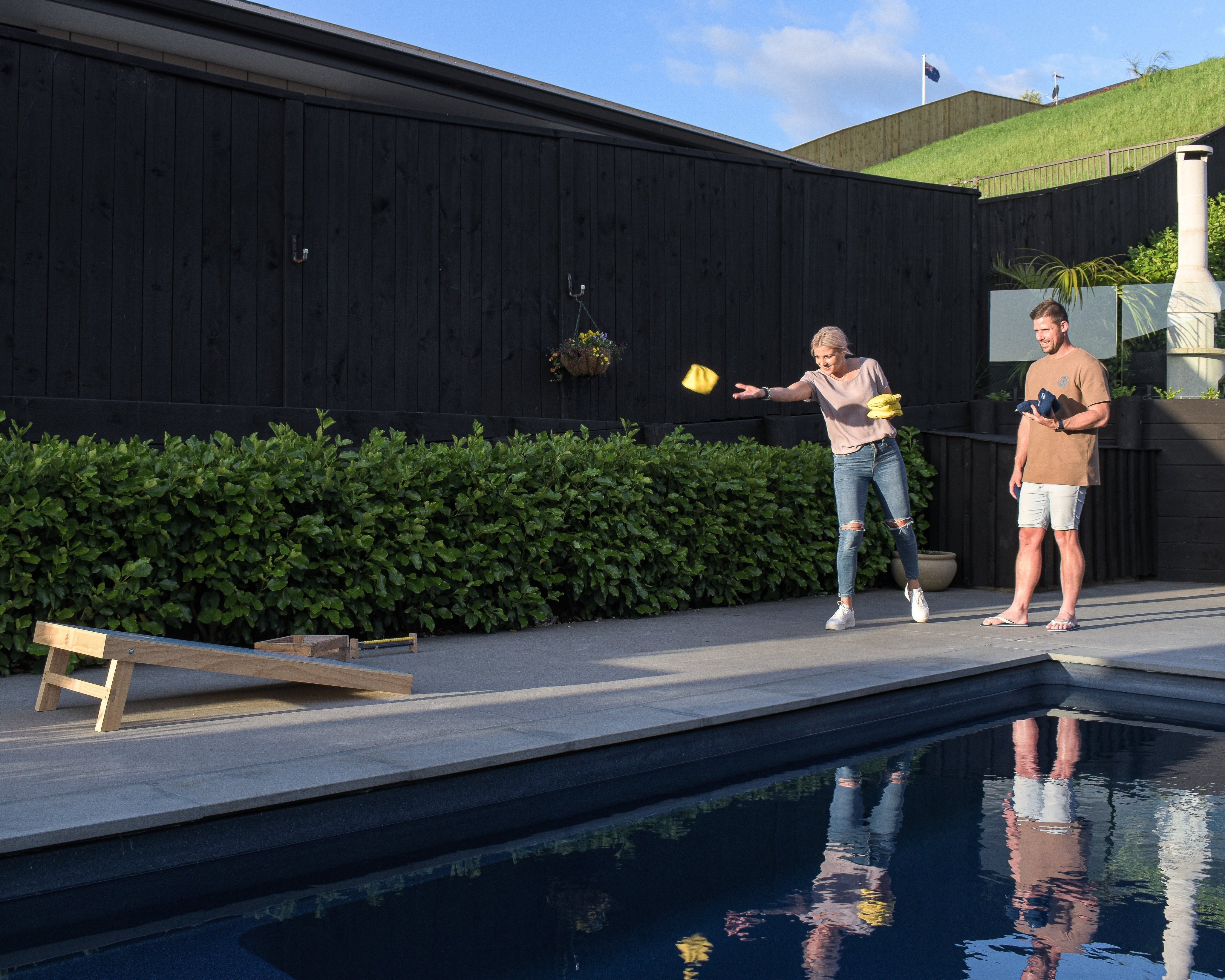Couple playing Cornhole by pool