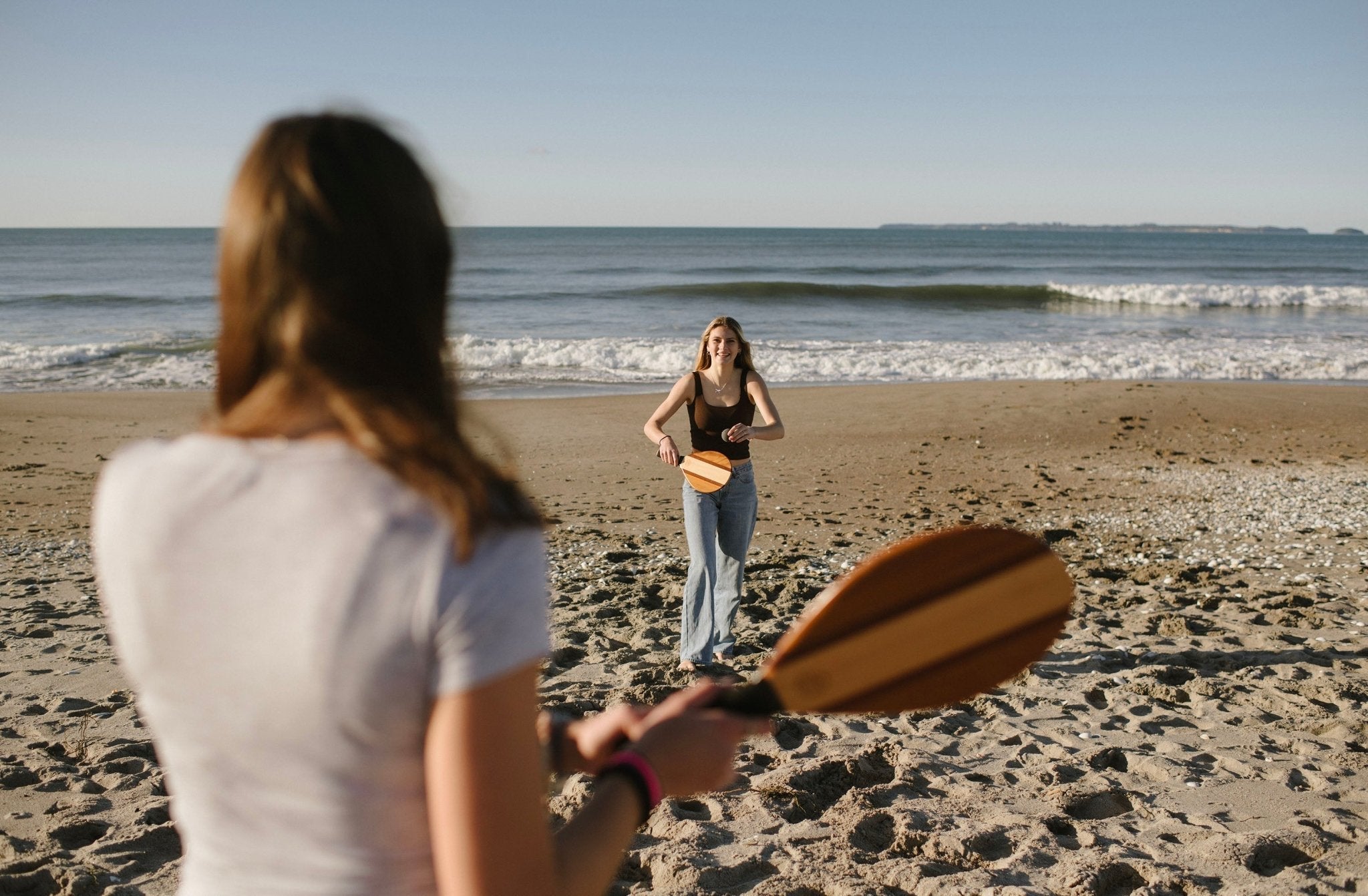 Two girls playing Beach Tennis by the ocean