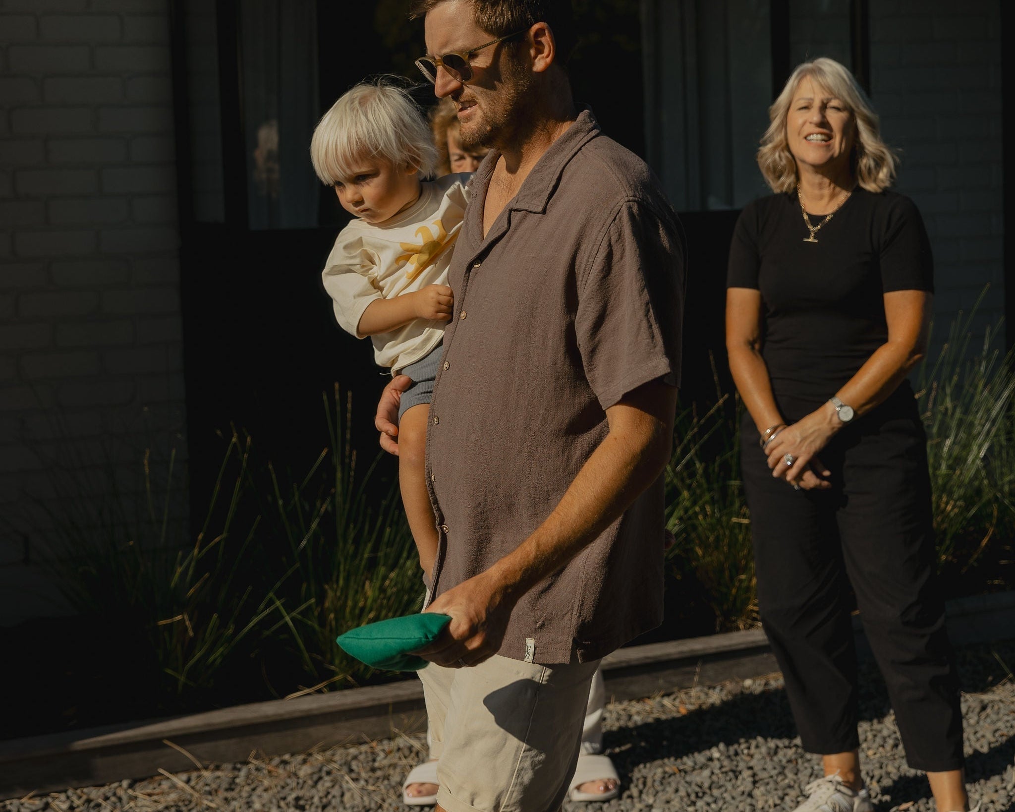 dad holding child while playing cornhole