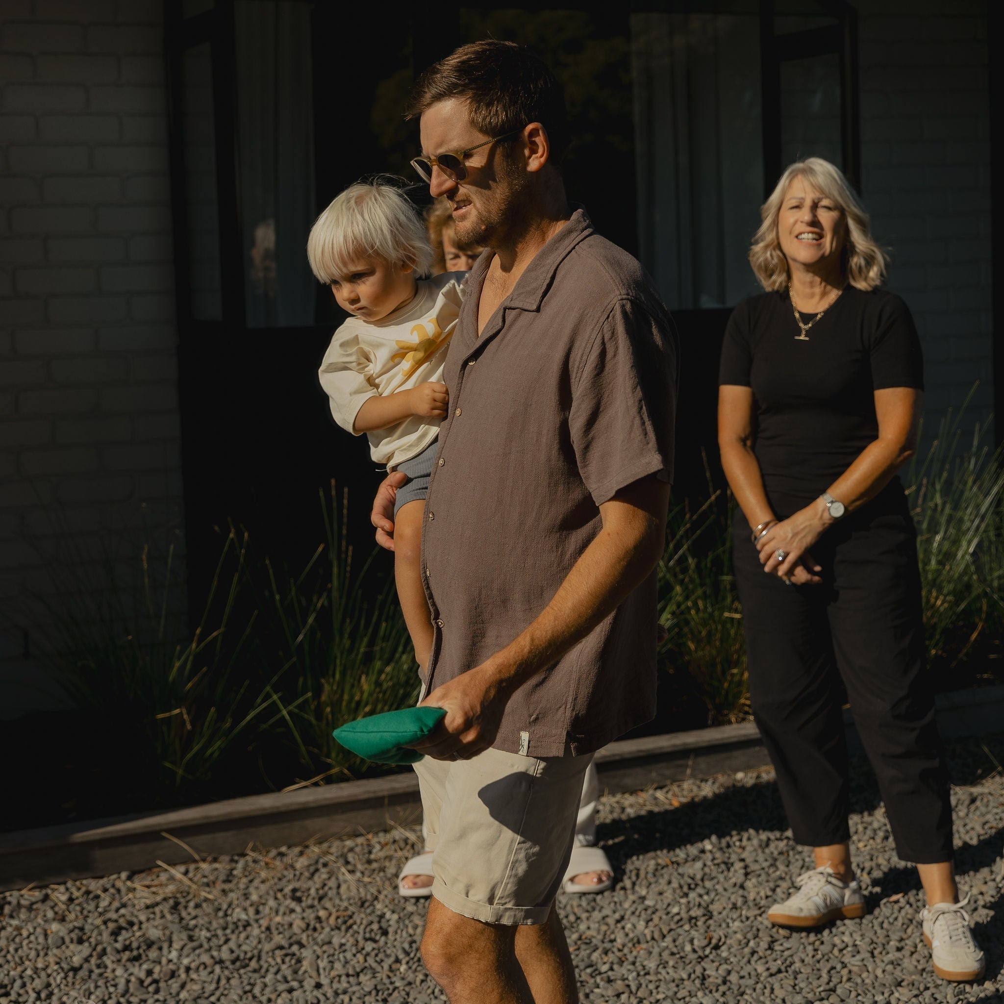 dad holding child while playing cornhole