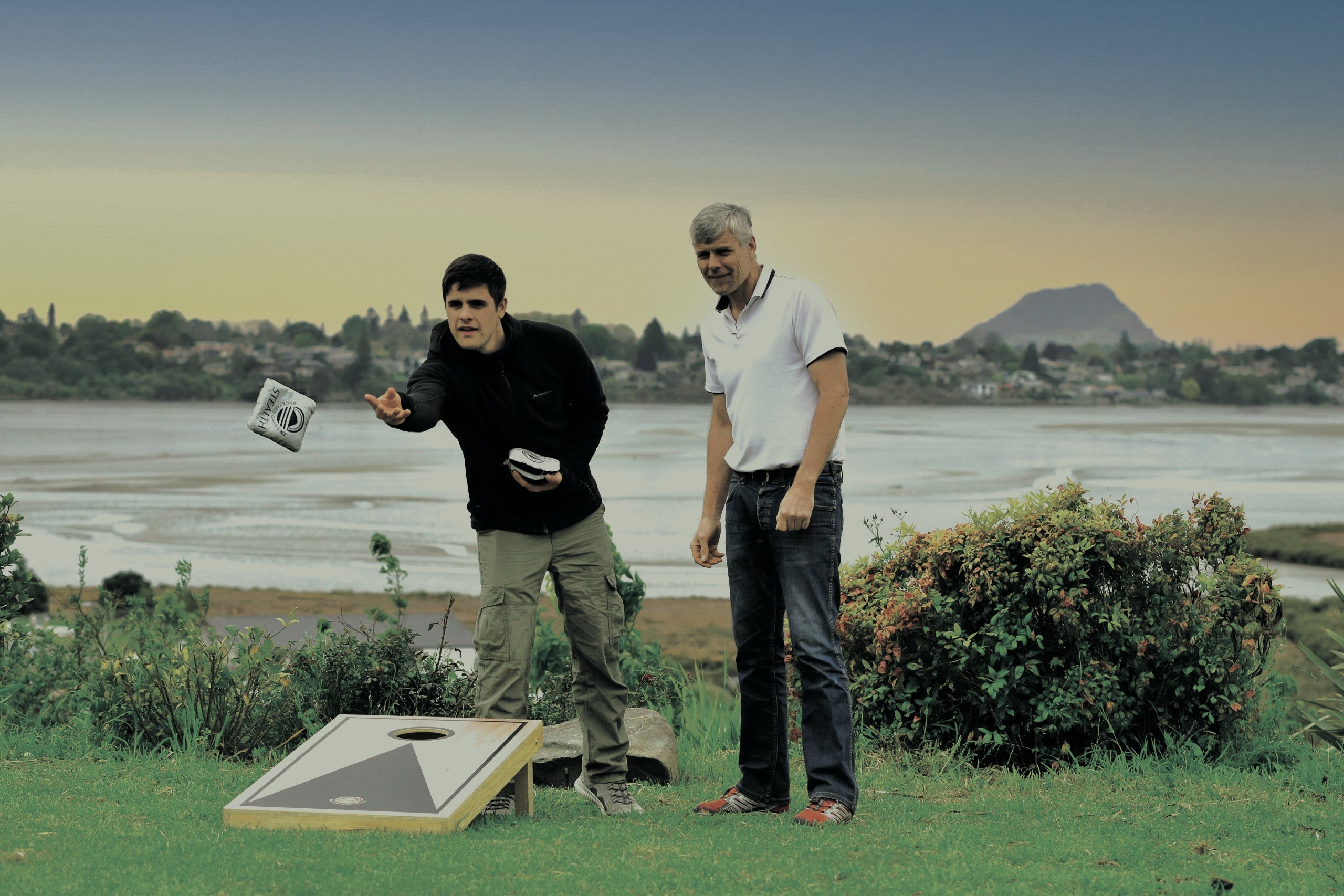 Father and son playing Cornhole in backyard