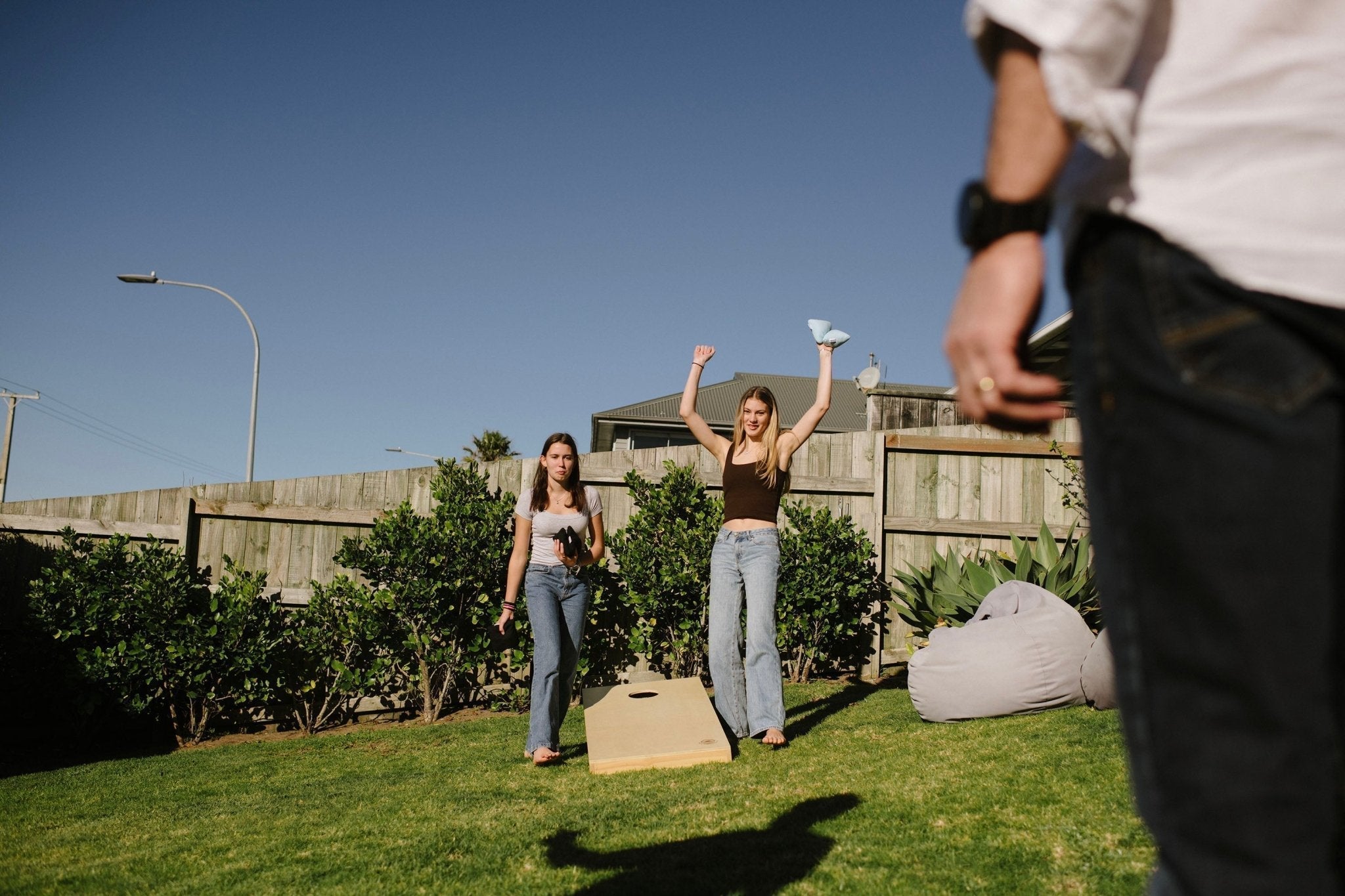 Girls celebrating Cornhole win in backyard 