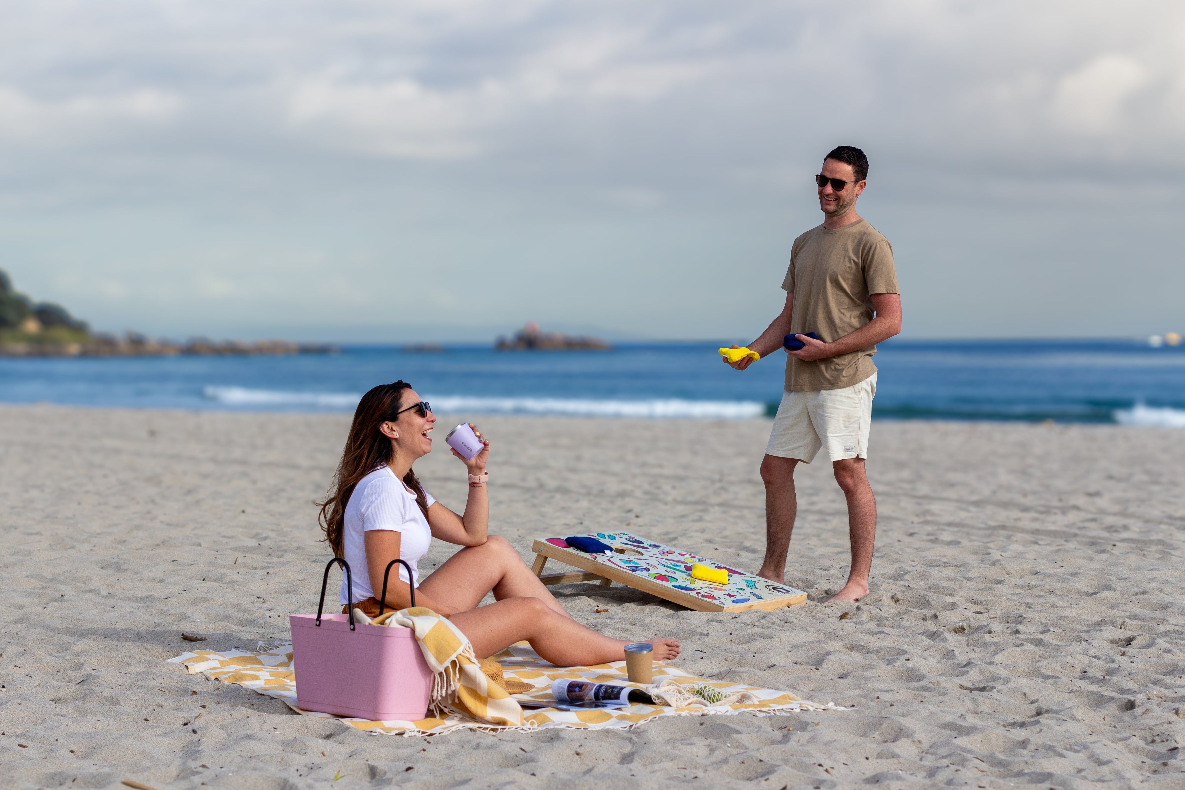 Couple laughing on the beach playing Cornhole