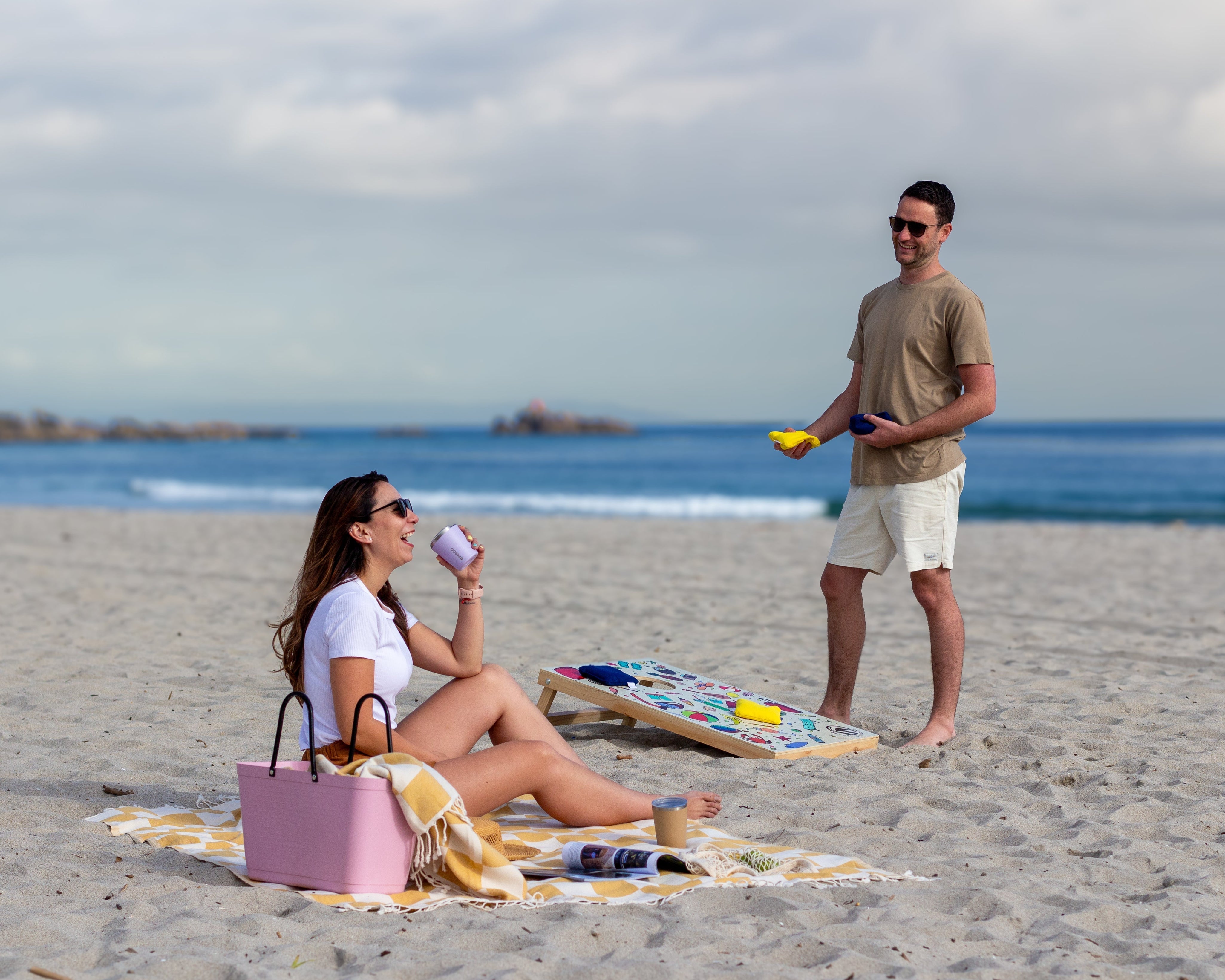 Couple laughing on the beach playing Cornhole