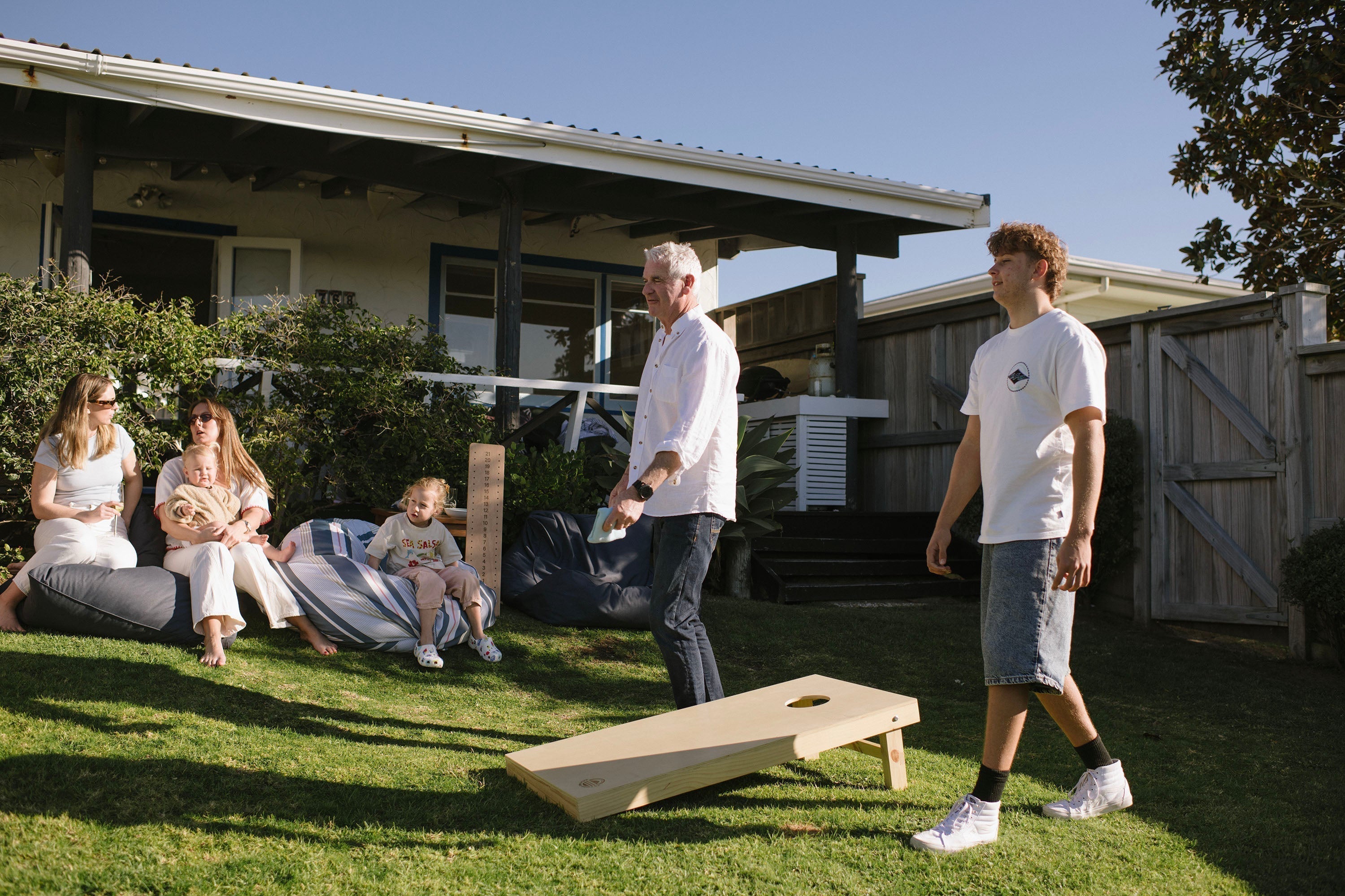Family playing Cornhole in Backyard