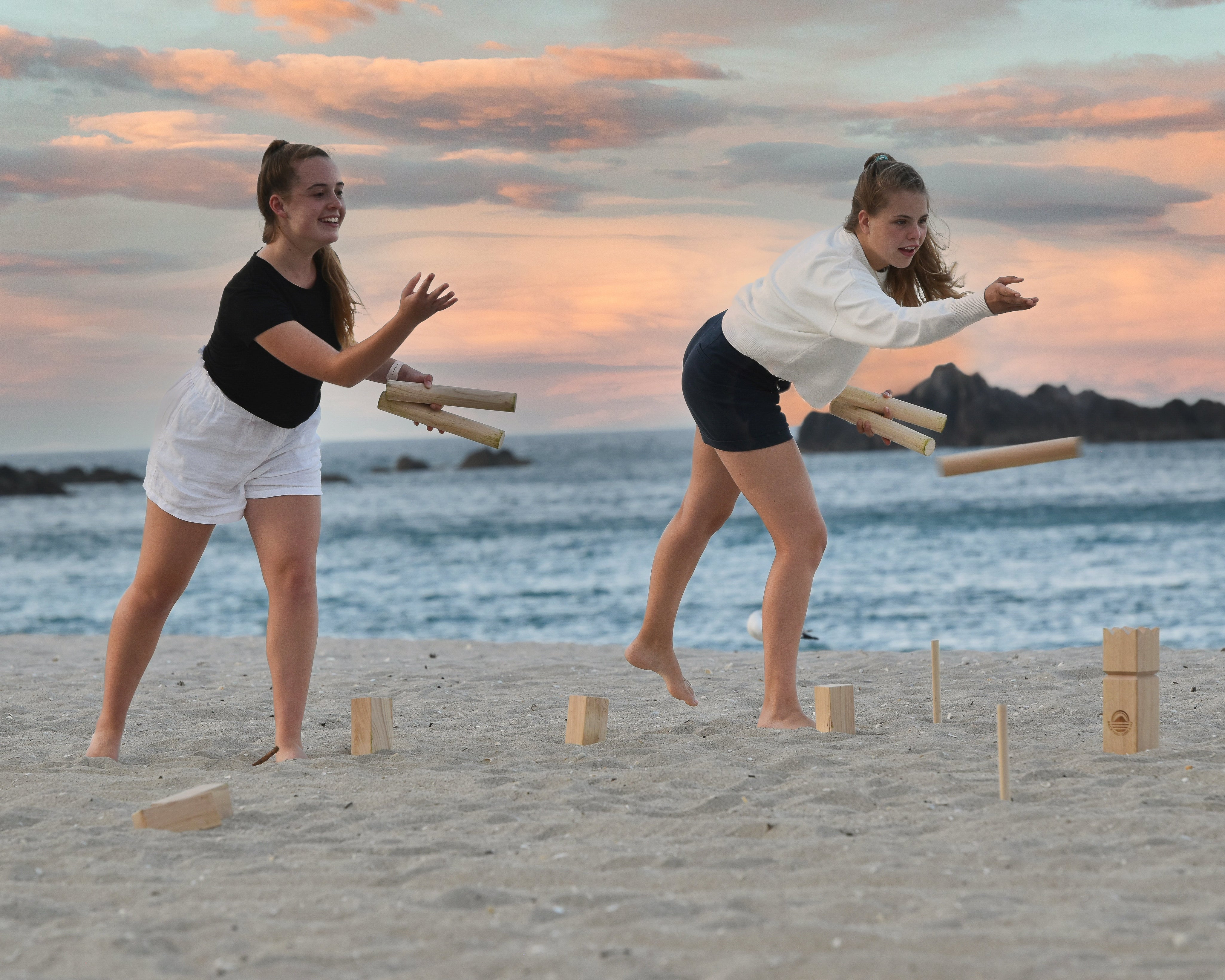 Two girls throwing Kubb sticks on the beach