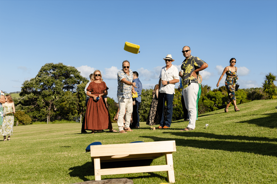 Man throwing Cornhole bag at Cornhole board at outdoor wedding