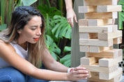 women pulling block from tumbling tower