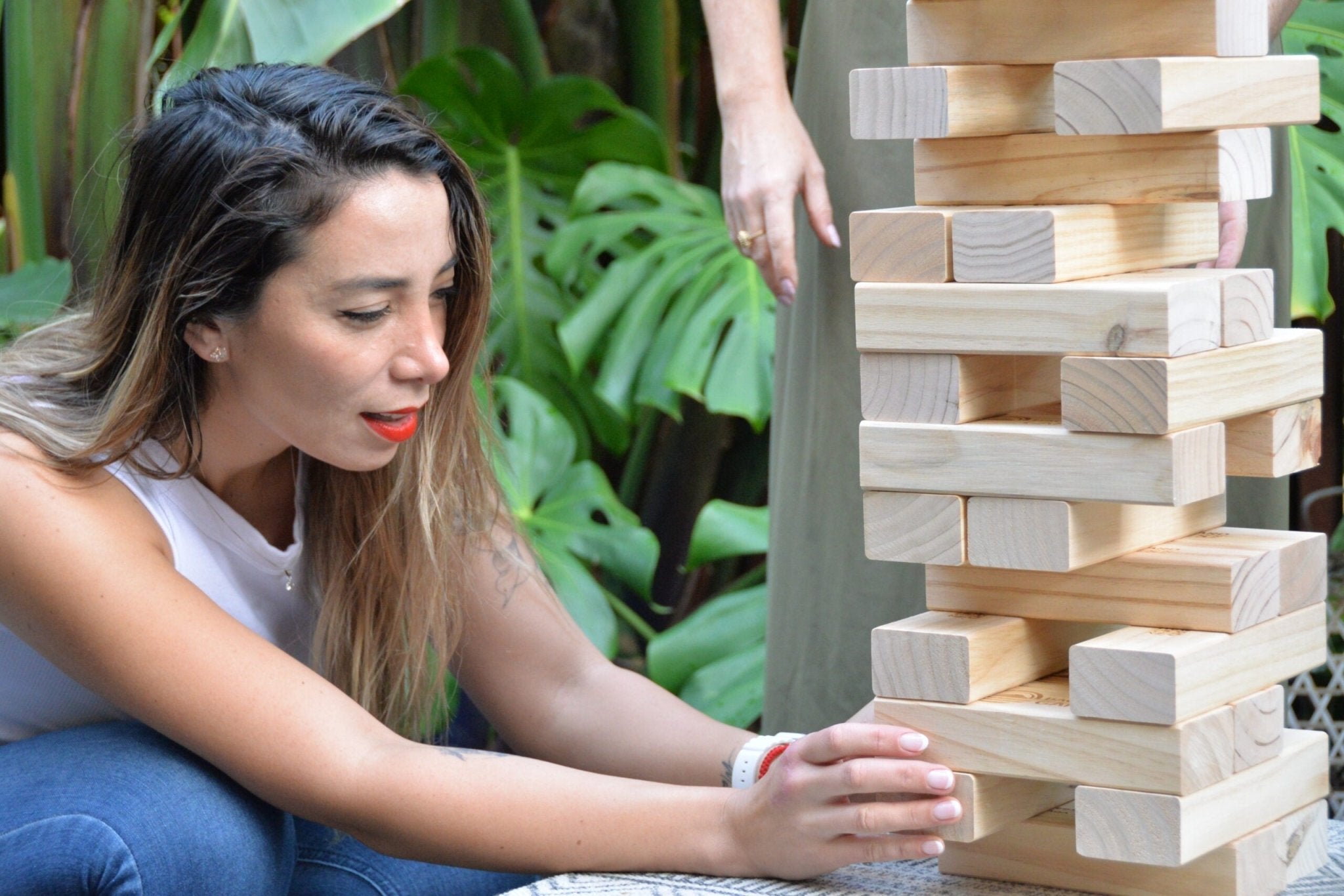 women pulling block from tumbling tower