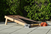 Deluxe Wood Cornhole Set — black-on-wood finish on an outdoor deck