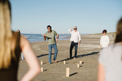 People playing a game of Giant Kubb on a beach
