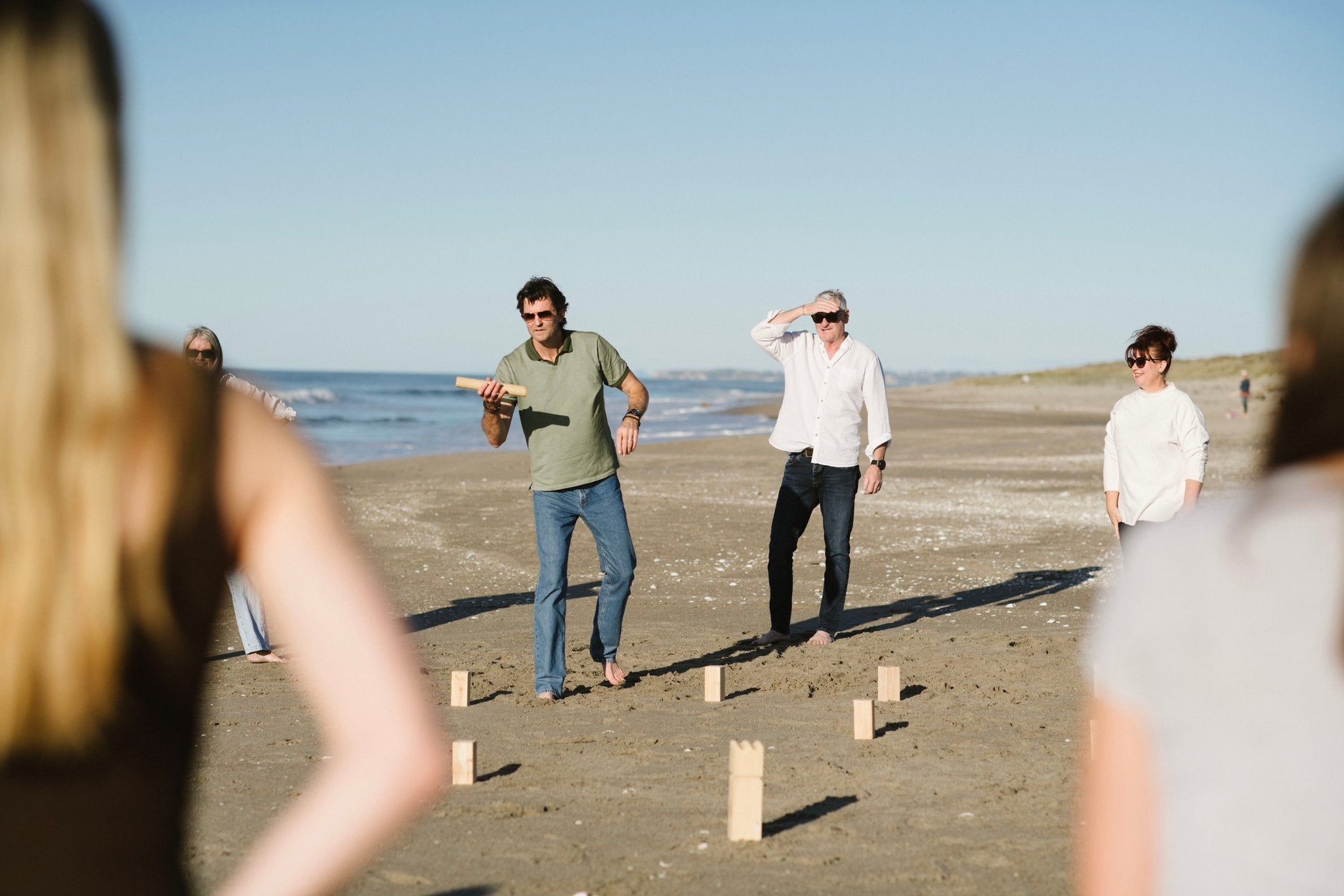 People playing a game of Giant Kubb on a beach