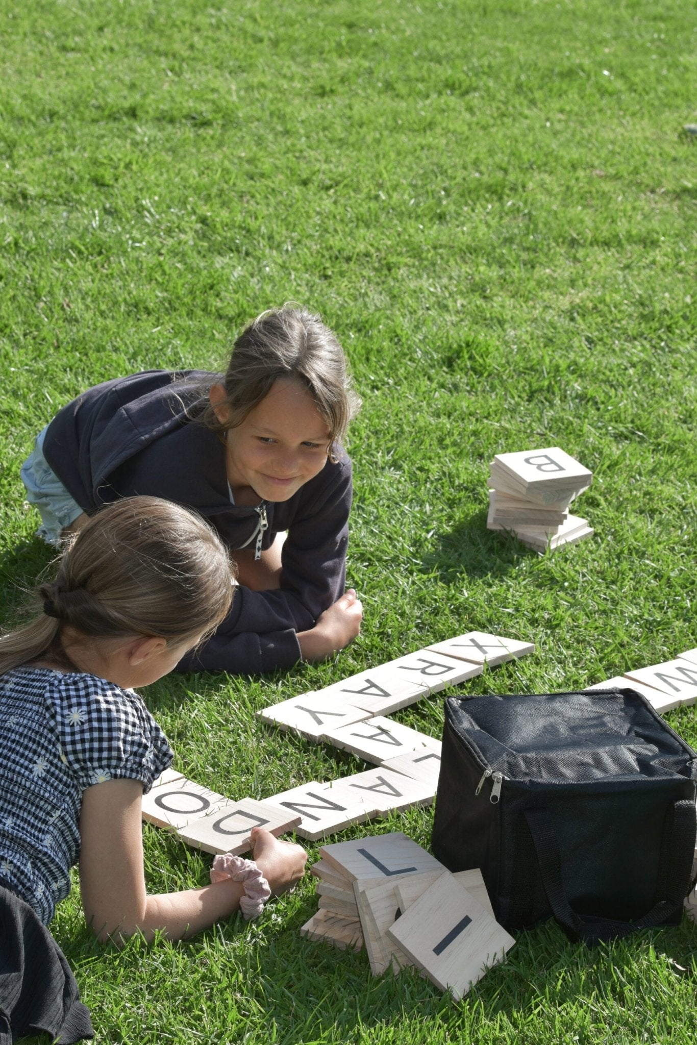 Two Girls Playing Backyard Games Giant Letter Tiles on the lawn