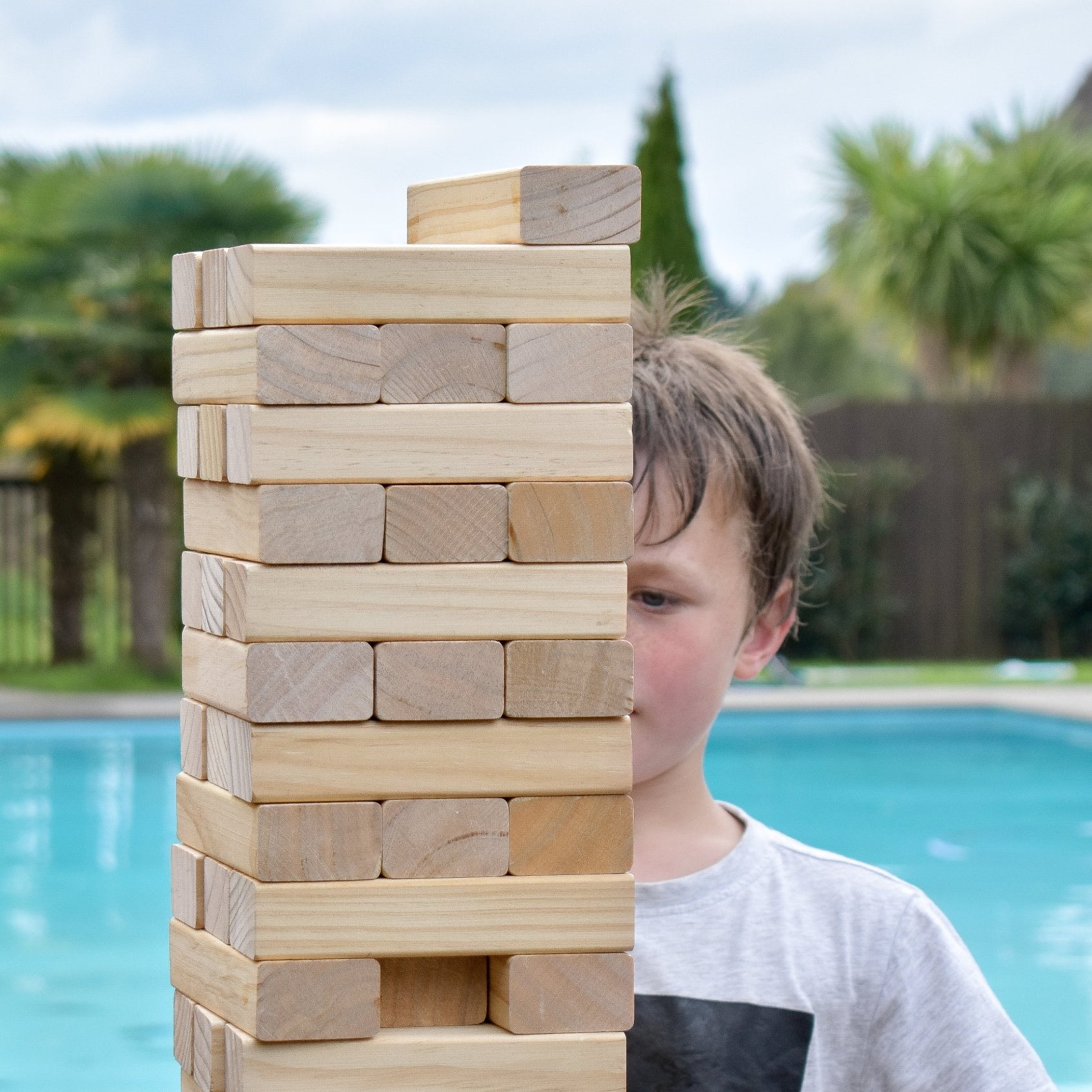 Child playing with Backyard Gaes NZ Giant Tumbling Tower by a pool