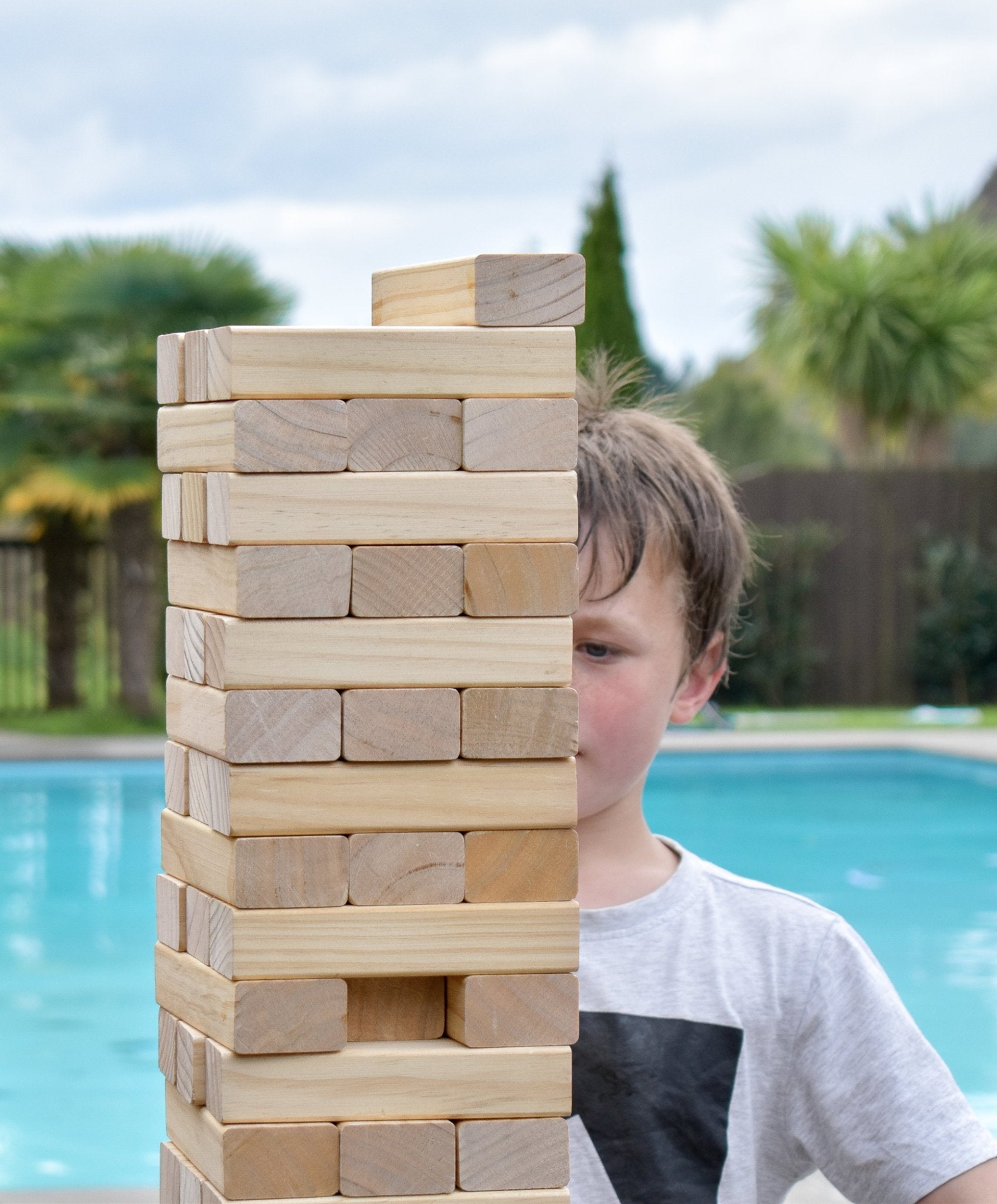 Child playing with Backyard Gaes NZ Giant Tumbling Tower by a pool