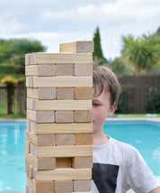 Child playing with Backyard Gaes NZ Giant Tumbling Tower by a pool
