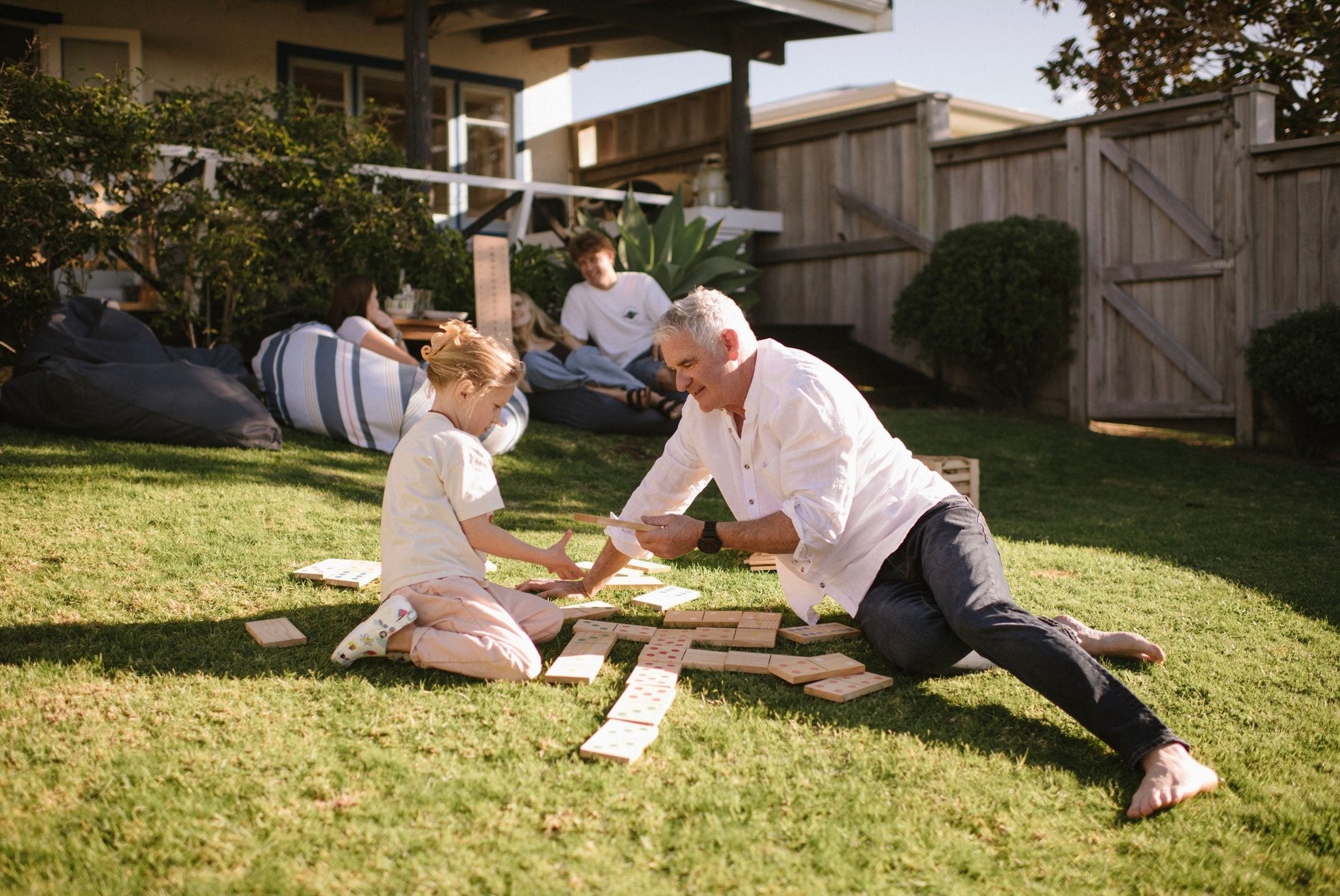 Man and child playing Backyard Games NZ Giant Dominoes on a grassy lawn