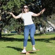 Woman standing on a Backyard Games NZ balance board in a park with trees and grass in the background