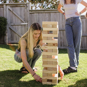 Two women playing with a Backyard Games NZ Super Giant Tumbling Tower outdoors.