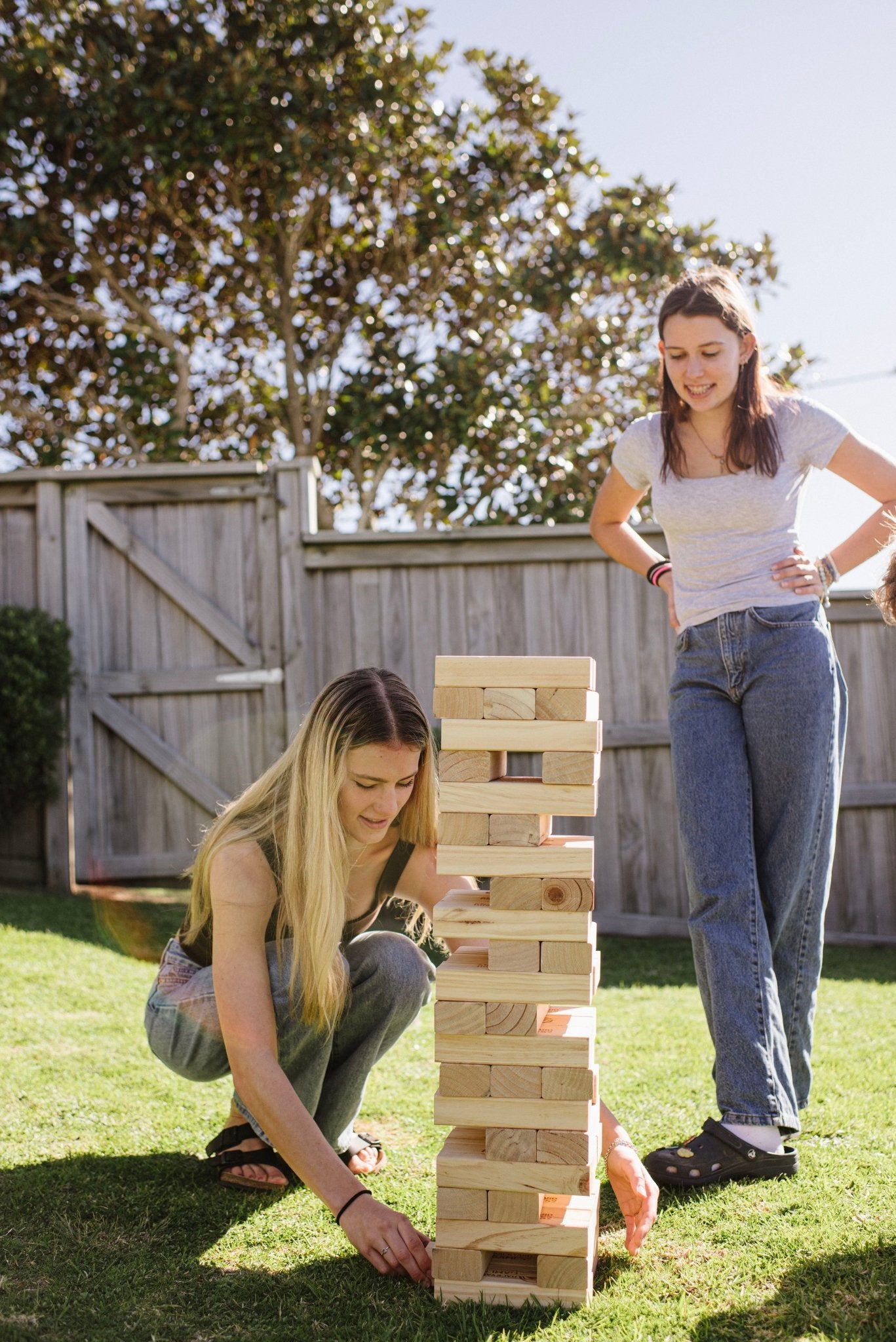 Two women playing with a Backyard Games NZ Super Giant Tumbling Tower outdoors.