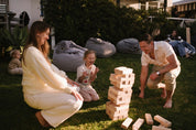 Family playing Backyard Games Giant Jenga outdoors on a grassy area