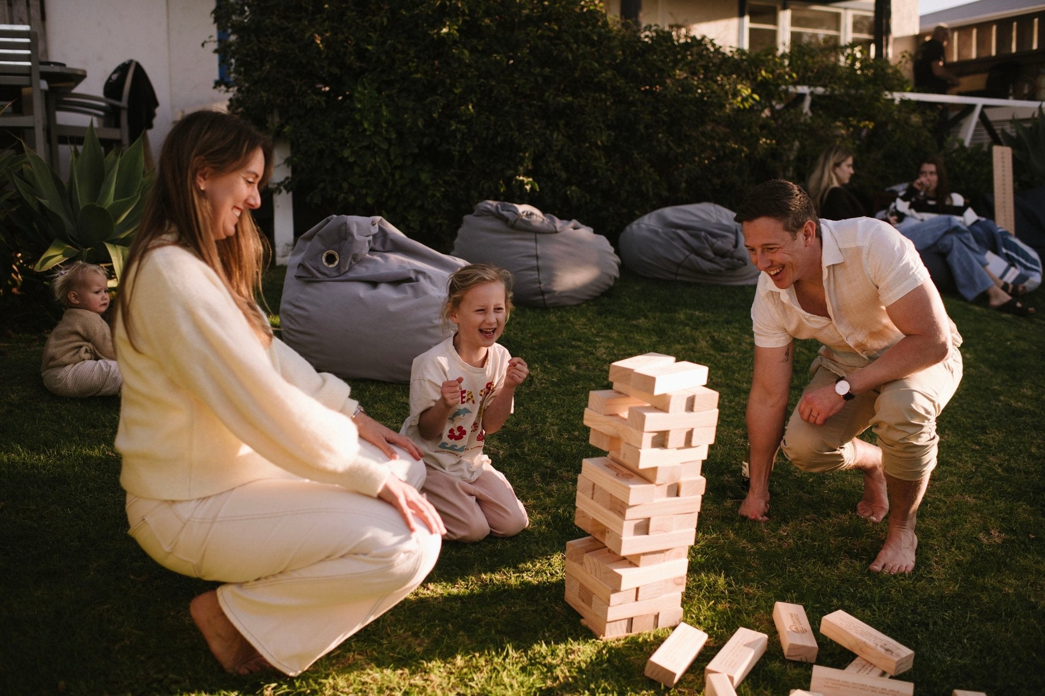 Family playing Backyard Games Giant Jenga outdoors on a grassy area