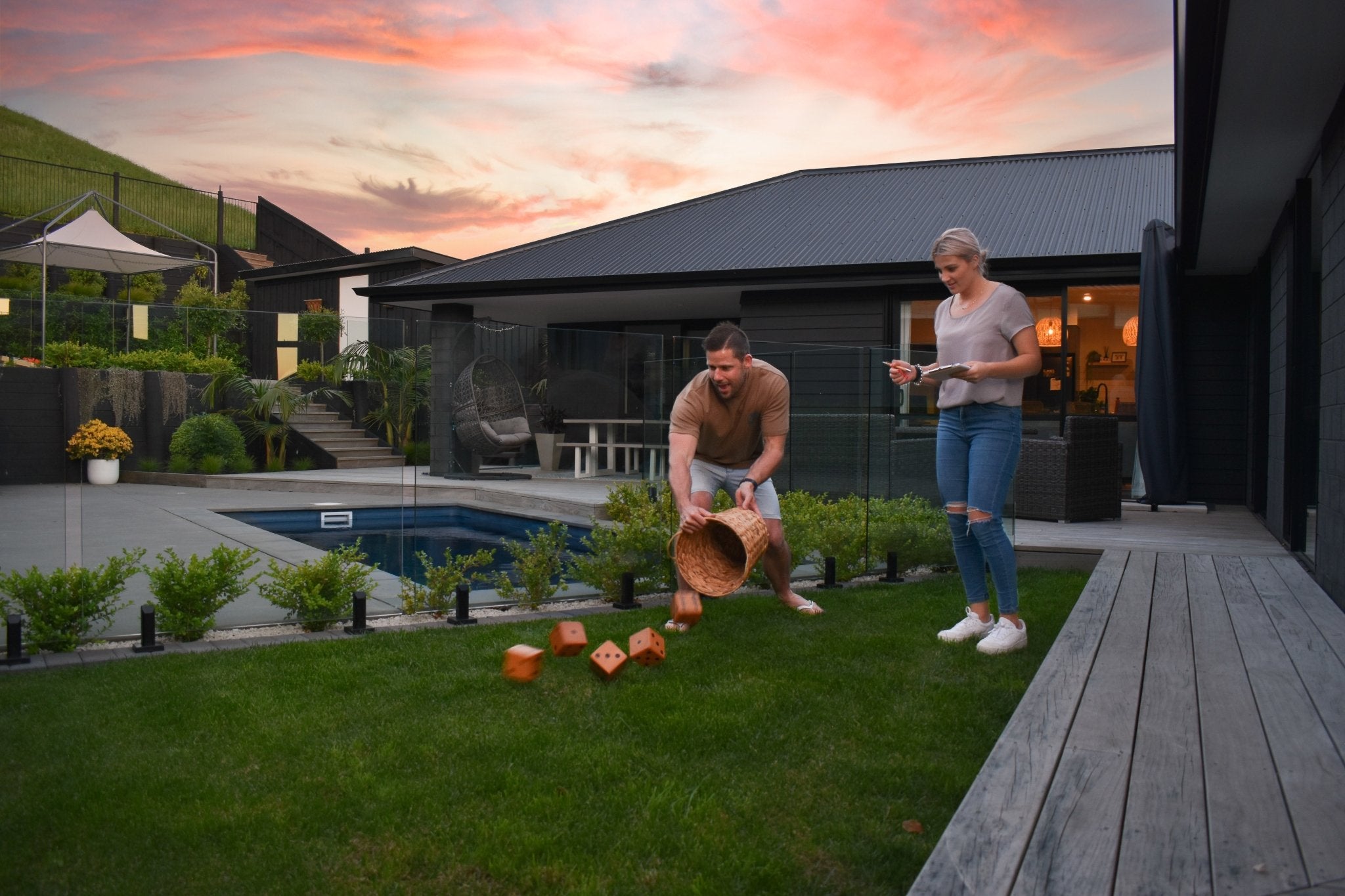 Two people playing Backyard Games NZ Yardzee and Farkle wooden dice set in their backyard. 